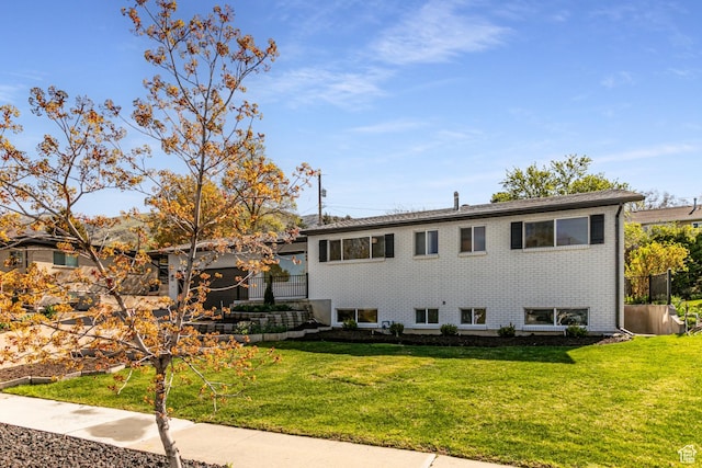 split level home featuring brick siding, a front lawn, and fence