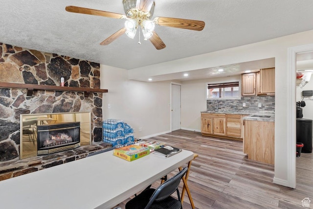 1971 N 3060 W, Clinton, UT 84015 - interior space with light wood finished floors, a stone fireplace, baseboards, a textured ceiling, and ceiling fan