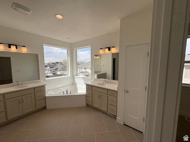 full bath with two vanities, visible vents, a garden tub, and a sink