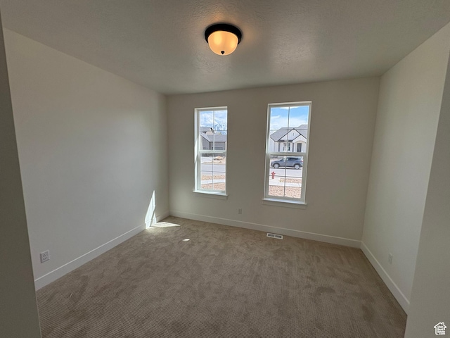 empty room with plenty of natural light, visible vents, and carpet