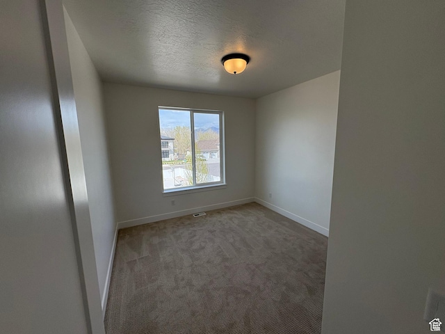 carpeted spare room with visible vents, baseboards, and a textured ceiling