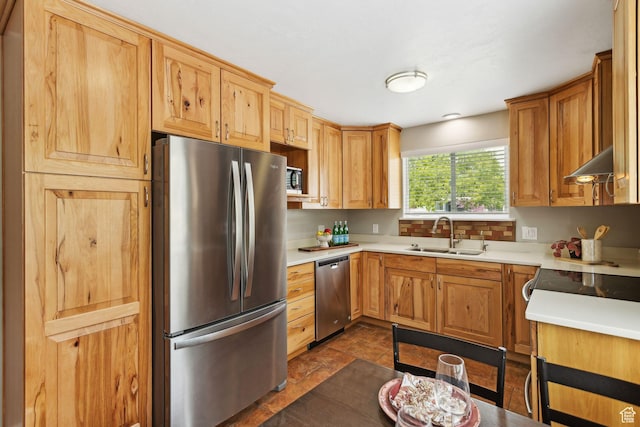 kitchen featuring a sink, under cabinet range hood, stainless steel appliances, stone finish flooring, and light countertops