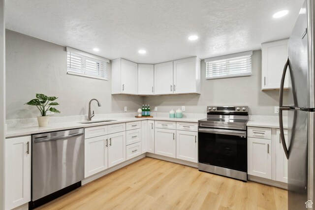 kitchen featuring stainless steel appliances, light countertops, a sink, and white cabinetry