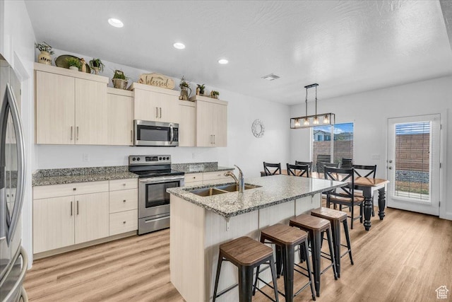 1519 E Honeycomb Dr S, St George, UT 84790 - kitchen with appliances with stainless steel finishes, a sink, a breakfast bar area, light wood finished floors, and stone counters