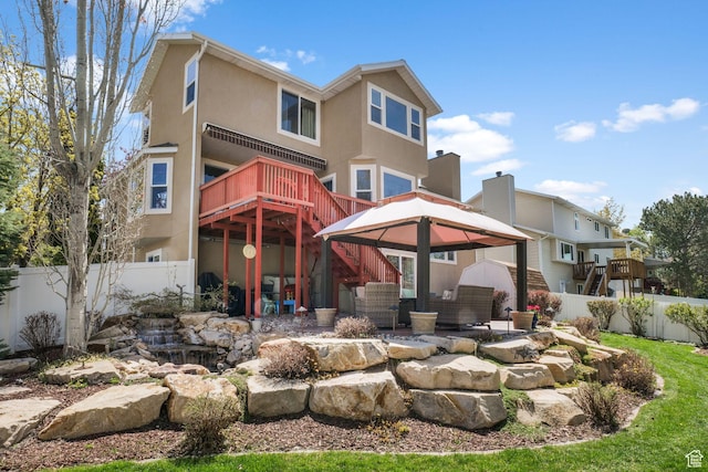 back of property featuring fence, a gazebo, stairs, and stucco siding
