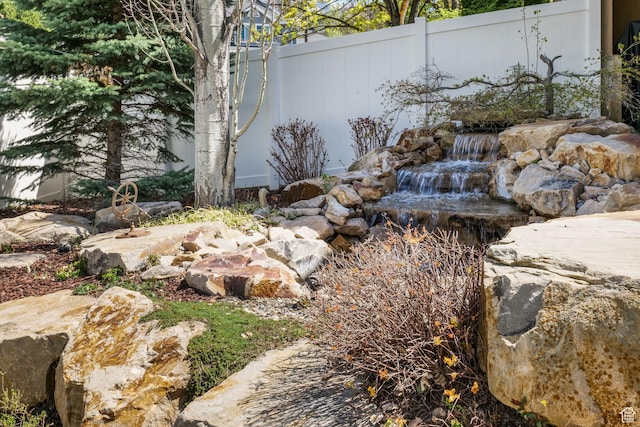 view of yard with fence and a garden pond