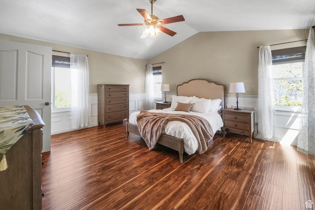 bedroom with wainscoting, vaulted ceiling, multiple windows, and wood finished floors