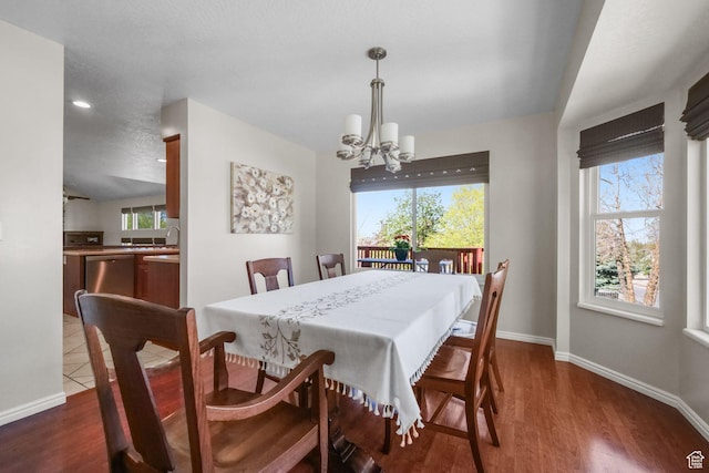 dining area featuring baseboards, a healthy amount of sunlight, a chandelier, and dark wood-style floors