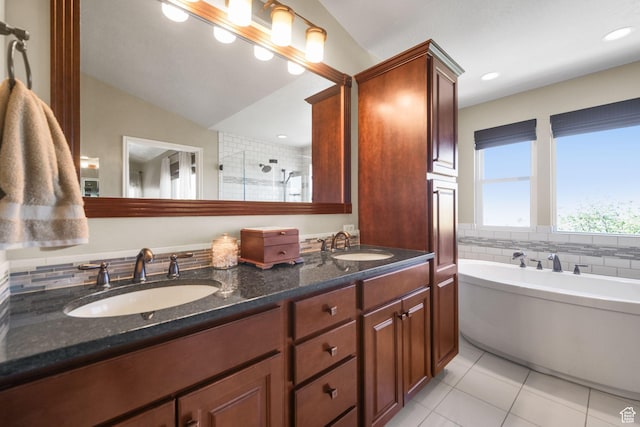 full bathroom featuring a shower stall, a freestanding tub, tile patterned flooring, and a sink