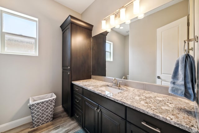 bathroom featuring baseboards, toilet, vanity, and wood finished floors