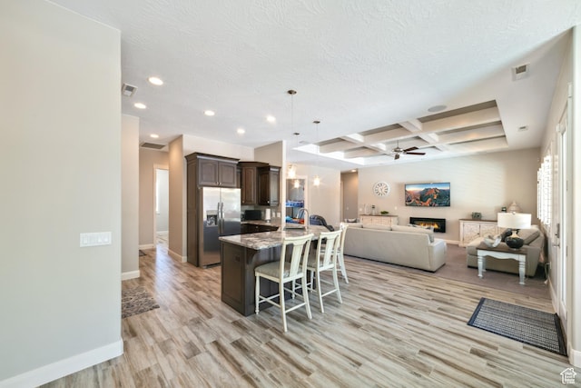 kitchen featuring open floor plan, stainless steel fridge, ceiling fan, dark brown cabinetry, and coffered ceiling
