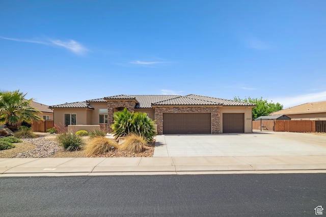view of front facade featuring stucco siding, a tiled roof, fence, and a garage