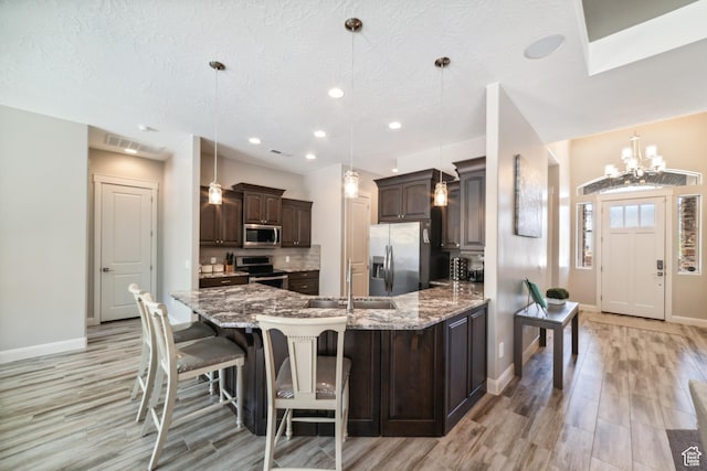 kitchen with light wood-style flooring, a sink, baseboards, dark brown cabinetry, and appliances with stainless steel finishes