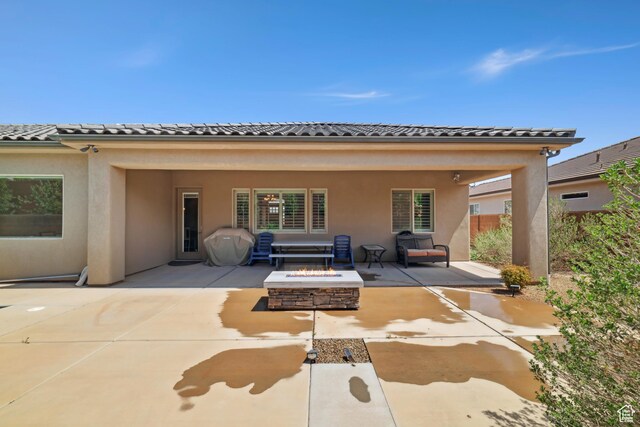 back of house featuring a fire pit, a tiled roof, a patio, and stucco siding