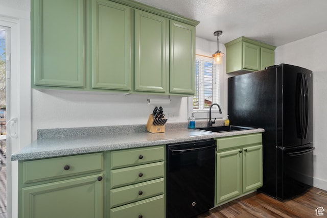 kitchen with dark wood-style floors, a sink, green cabinets, light countertops, and black appliances