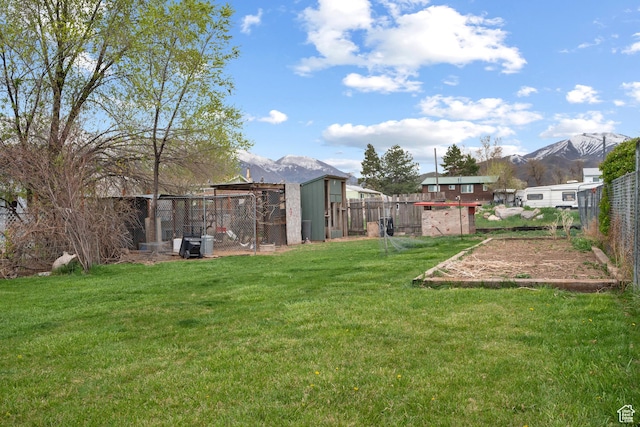 view of yard featuring exterior structure, a fenced backyard, and a mountain view