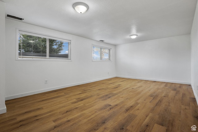 spare room with wood finished floors, a textured ceiling, and baseboards