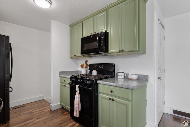 kitchen with black appliances, green cabinets, dark wood finished floors, baseboards, and visible vents