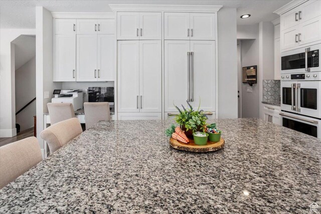 364 W Clark Cir, Farmington, UT 84025 - kitchen with white appliances, stone countertops, white cabinets, recessed lighting, and a kitchen breakfast bar