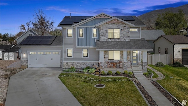 view of front of home with a yard, solar panels, board and batten siding, a porch, and stone siding