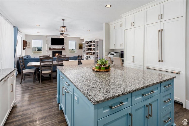 364 W Clark Cir, Farmington, UT 84025 - kitchen with blue cabinets, a ceiling fan, white cabinets, dark wood finished floors, and a large fireplace