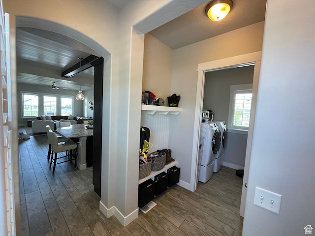 corridor featuring arched walkways, baseboards, washer and clothes dryer, and dark wood finished floors