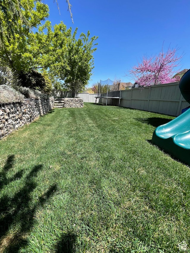 view of yard featuring a fenced backyard and a trampoline