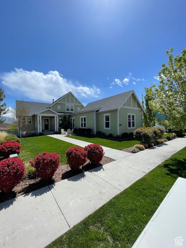 view of front facade with roof with shingles, a front lawn, and concrete driveway