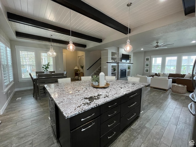 kitchen with a glass covered fireplace, baseboards, dark cabinetry, and wood-type flooring