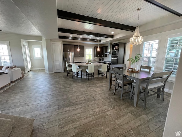 dining space featuring beamed ceiling, a notable chandelier, dark wood finished floors, and baseboards