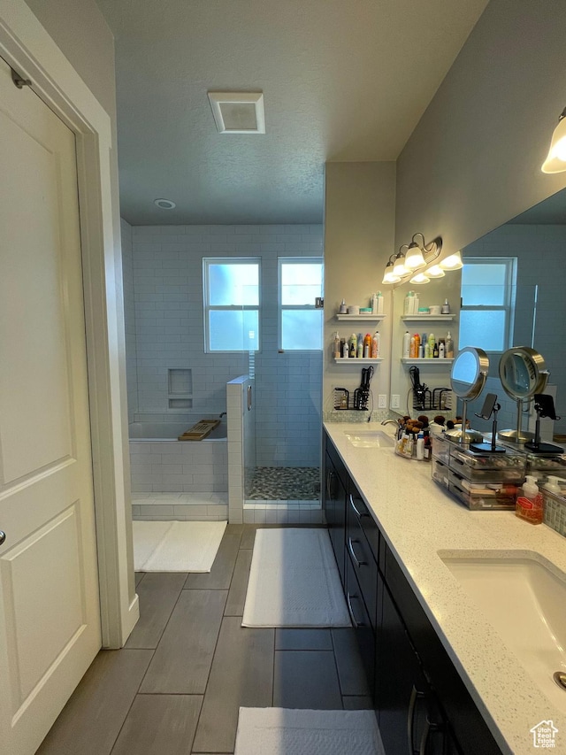 bathroom with tiled shower, a garden tub, double vanity, and a sink