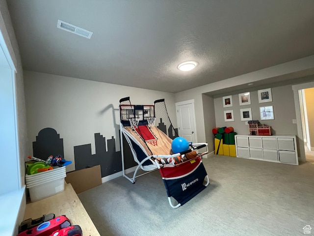 recreation room featuring baseboards, visible vents, a textured ceiling, and carpet
