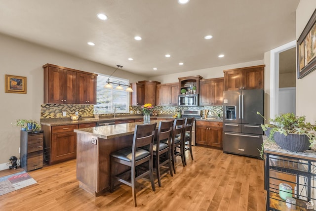 3627 W Augusta Dr, Syracuse, UT 84075 - kitchen featuring stainless steel appliances, light wood-style flooring, a kitchen island, a breakfast bar, and decorative backsplash