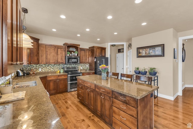 3627 W Augusta Dr, Syracuse, UT 84075 - kitchen with appliances with stainless steel finishes, a sink, a kitchen island, light wood-style flooring, and recessed lighting