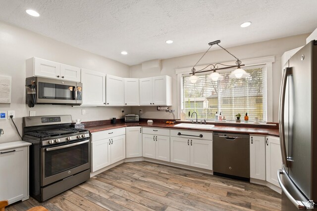 290 N 300 E, Springville, UT 84663 - kitchen featuring a textured ceiling, a sink, stainless steel appliances, light wood-style flooring, and white cabinets