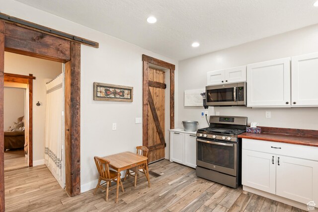290 N 300 E, Springville, UT 84663 - kitchen with a barn door, recessed lighting, stainless steel appliances, light wood-style floors, and wood counters