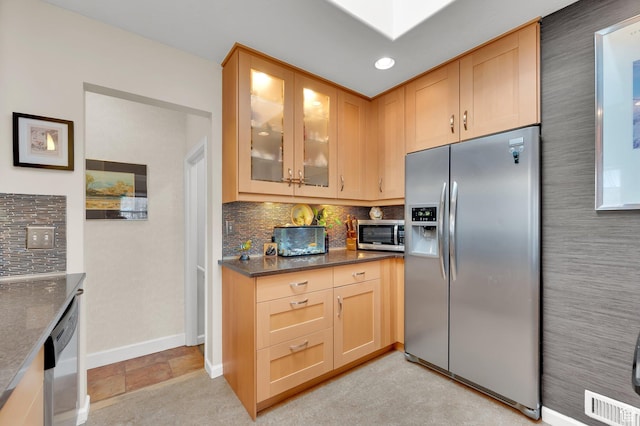 kitchen featuring stainless steel appliances, baseboards, tasteful backsplash, glass insert cabinets, and light brown cabinets