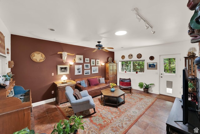living room featuring a ceiling fan, baseboards, and rail lighting