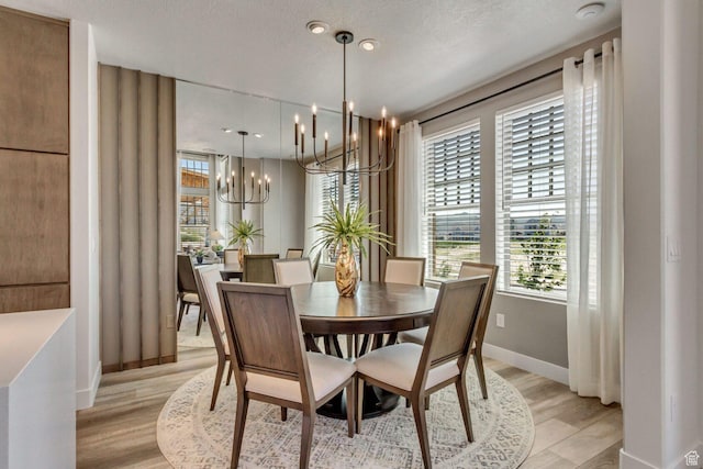 dining space with light wood-style flooring, baseboards, a chandelier, and a healthy amount of sunlight