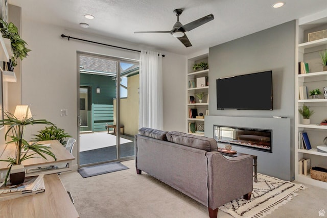 living area featuring recessed lighting, carpet, a ceiling fan, a glass covered fireplace, and built in features
