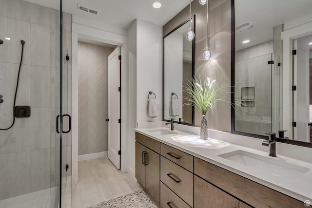 full bathroom featuring double vanity, a sink, visible vents, and a stall shower