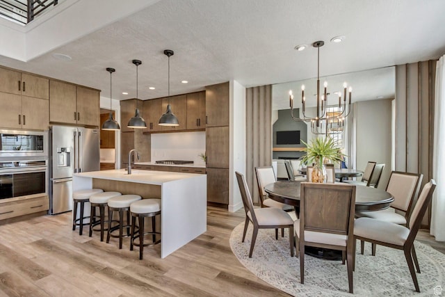dining room with recessed lighting, a textured ceiling, an inviting chandelier, and light wood-style floors