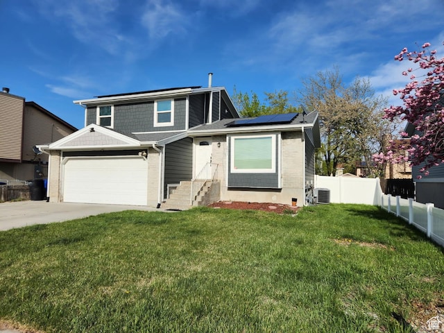 traditional home with central AC unit, fence, solar panels, driveway, and a front yard