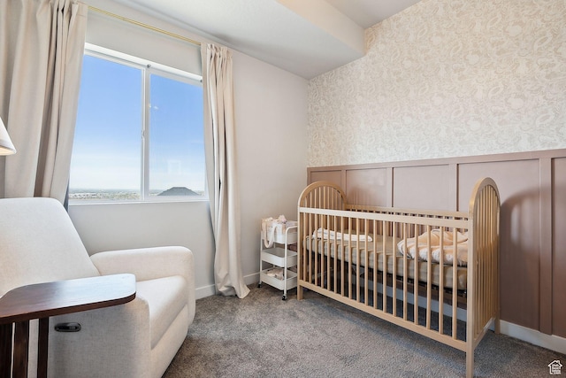 carpeted bedroom featuring wallpapered walls, a decorative wall, a crib, and wainscoting