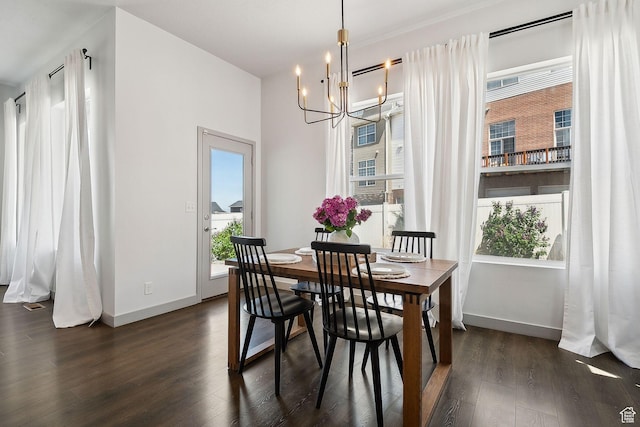dining area featuring dark wood-type flooring, baseboards, and a notable chandelier