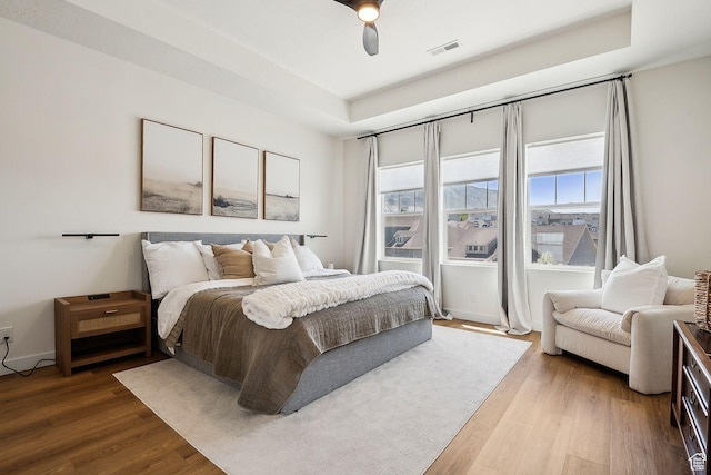 bedroom with baseboards, wood finished floors, visible vents, and a ceiling fan