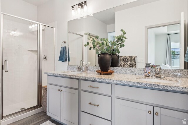 bathroom featuring a shower stall, a sink, and double vanity