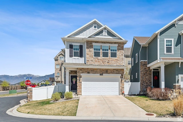 craftsman-style home with fence, concrete driveway, board and batten siding, stone siding, and a mountain view