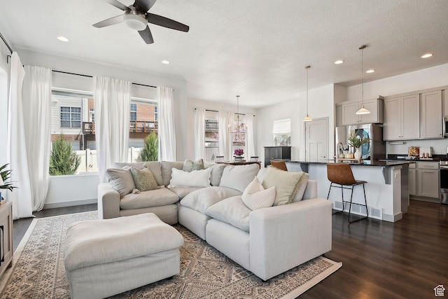 living area with a textured ceiling, recessed lighting, dark wood-type flooring, and ceiling fan