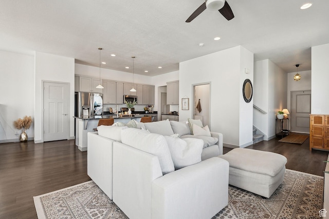 living room with stairs, ceiling fan, baseboards, dark wood-style flooring, and recessed lighting